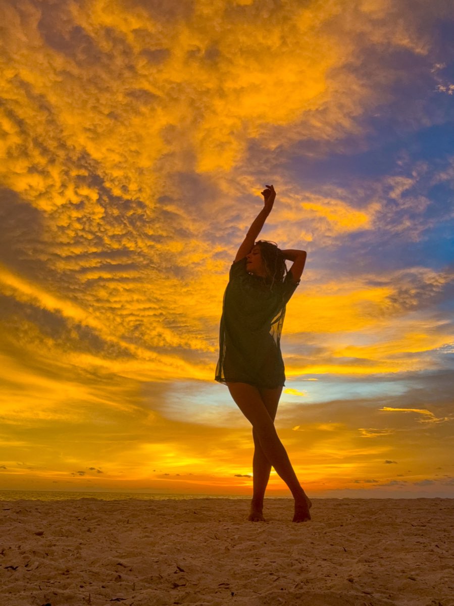 Elena Corrao on the beach at sunset, one arm raised